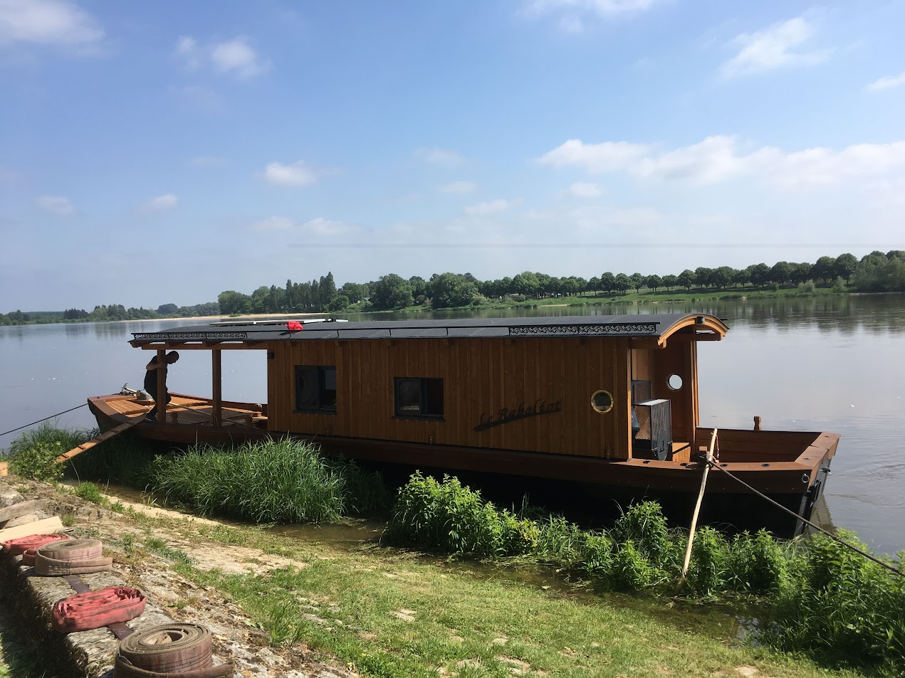 Péniche en bois sur fleuve paisible.