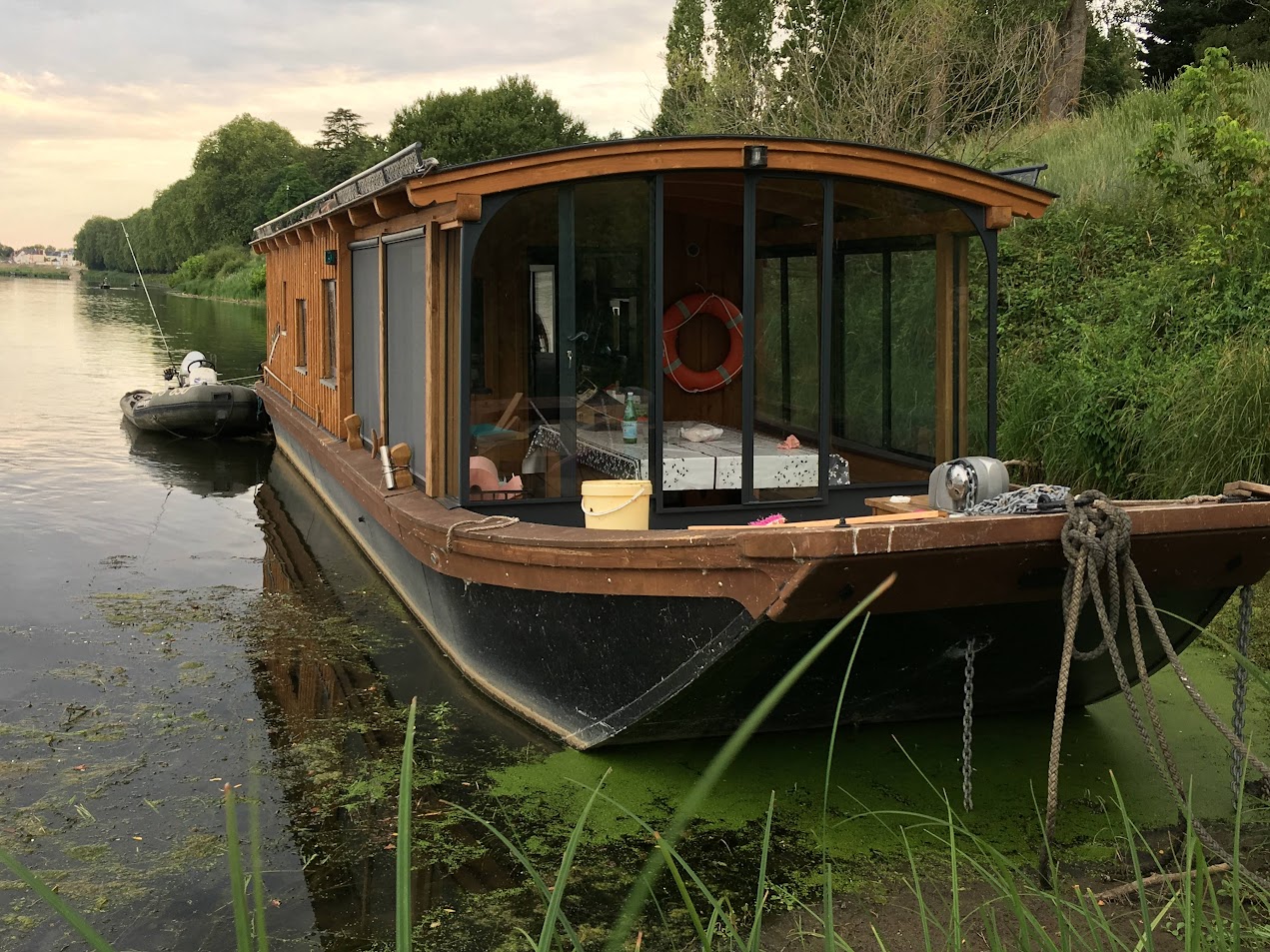 Péniche habitable amarrée au bord de l'eau.