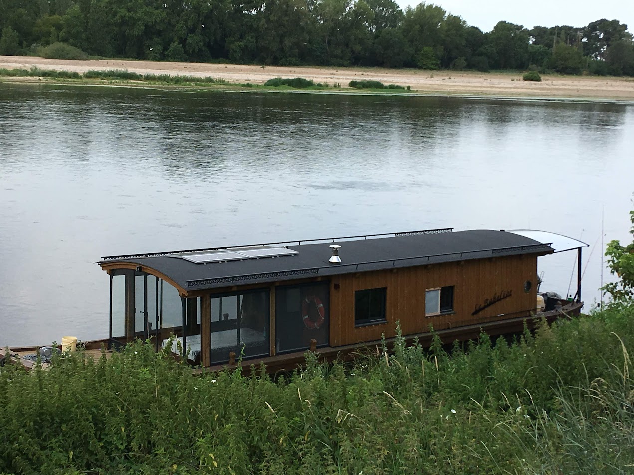 Maison flottante sur fleuve calme.