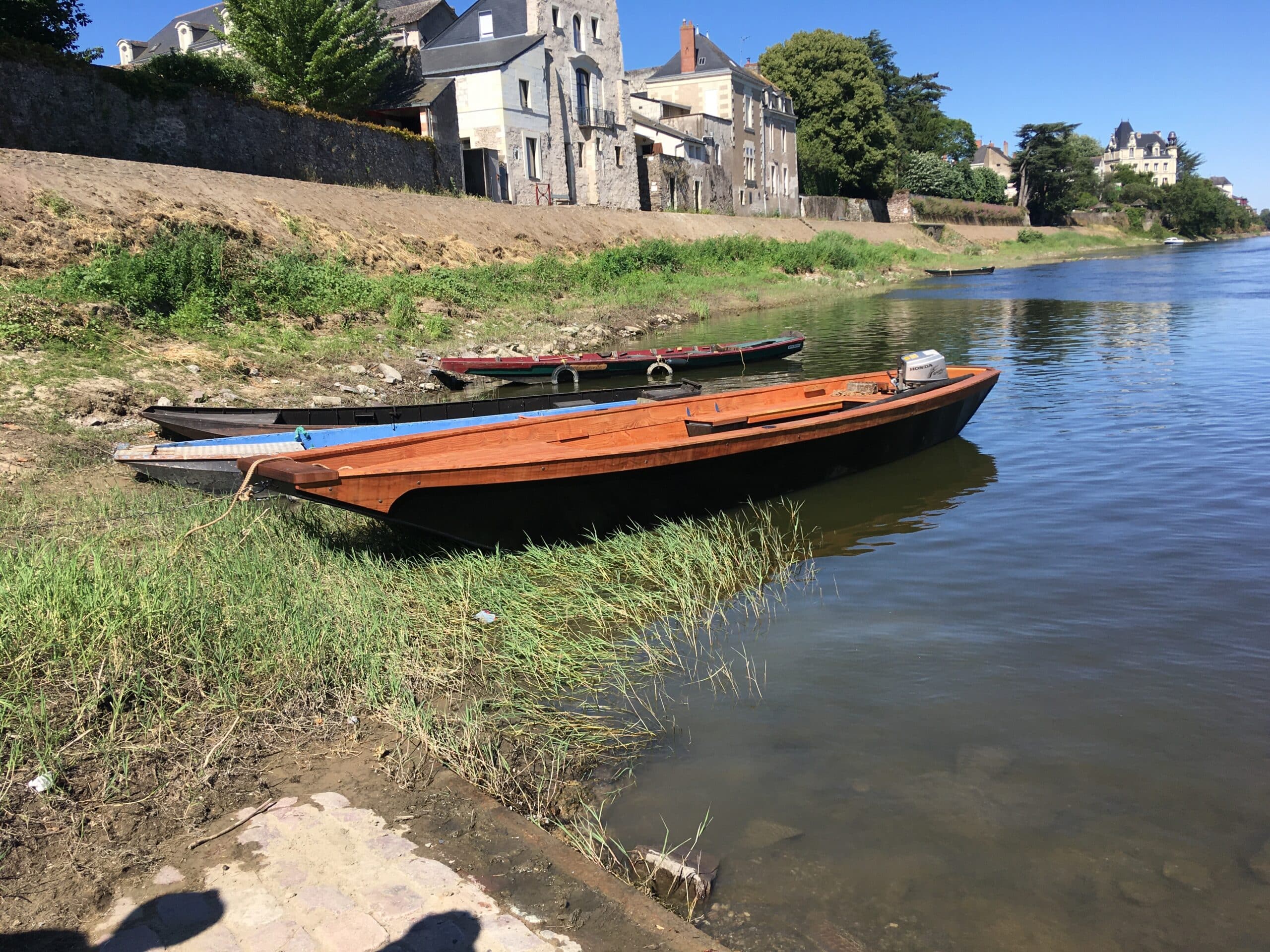 Barques sur rivière, ville historique en arrière-plan.